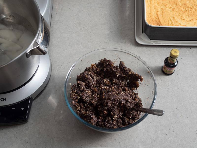 w szklanej misce masa makowa wymieszana z bakaliami, obok opakowanie ekstraktu migdałowego dr. oetkera oraz upieczone kruche ciasto w formie do pieczenia