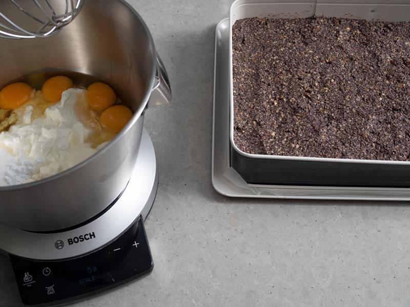 w misie robota kuchennego bosch składniki na masę serową do ciasta seromak, obok forma z wyłożoną na kruche ciasto warstwą makową