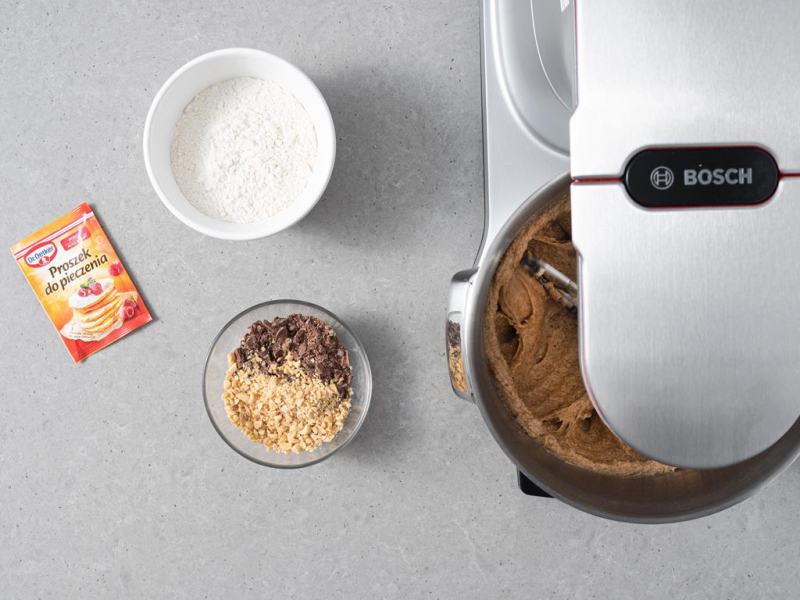 W miseczce mąka, obok proszek do pieczenia i w miseczce czekolada mleczna i orzechy arachidowe.