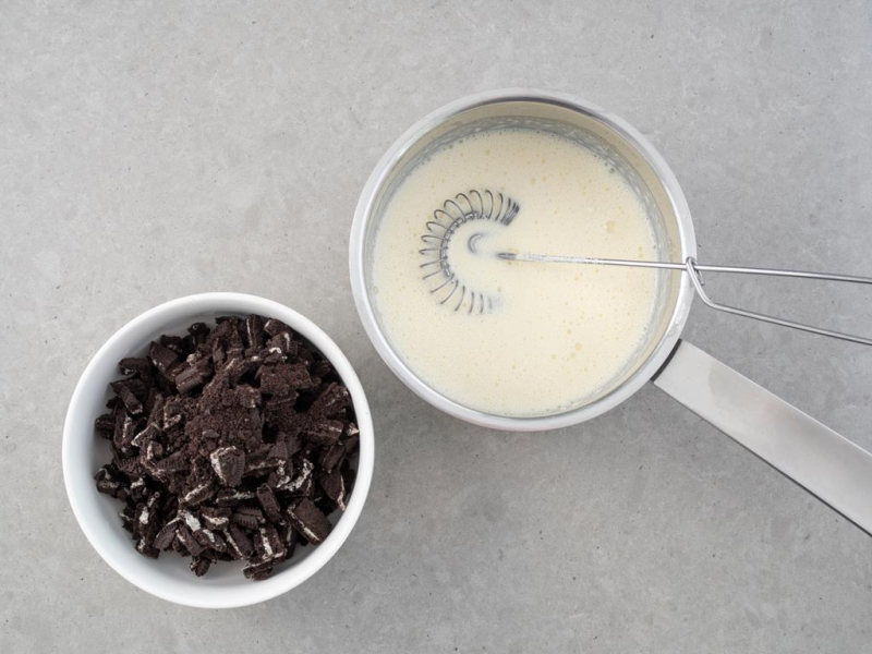 w miseczce ciasteczka oreo obok w rondelku śmietanka