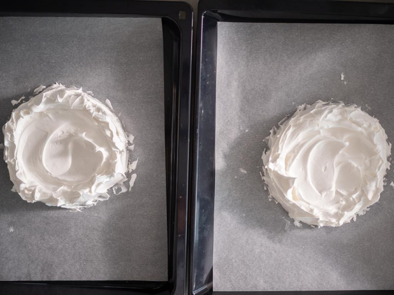 dwa blaty bezowe wyłożone na blachach do pieczenia