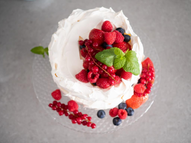 na paterze tort bezowy przyozdobiony świeżymi owocami