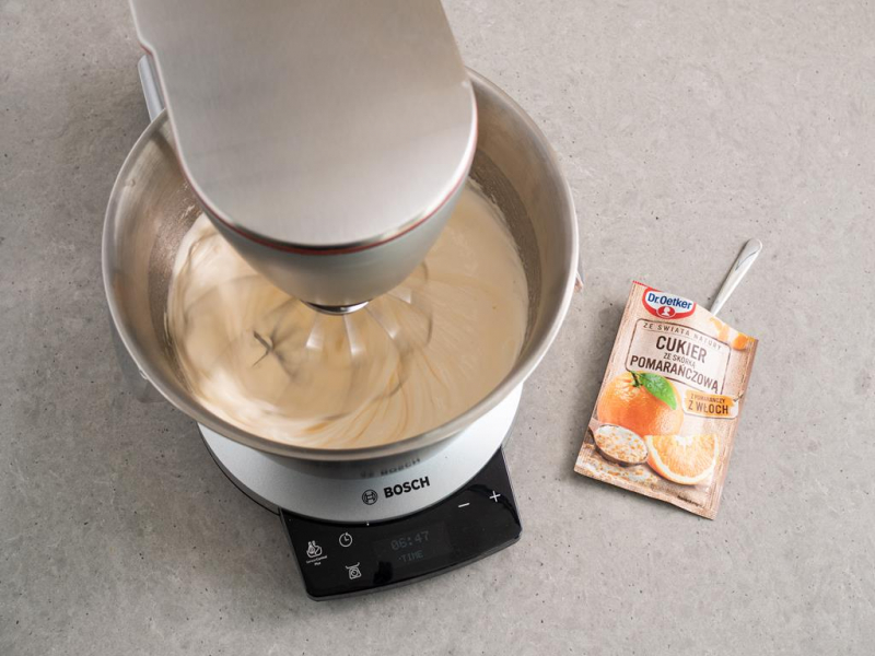 jajka ubite z cukrem w misie robota bosch, obok opakowanie cukru ze skórką pomarańczową dr. oetkera