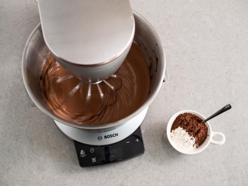 masa czekoladowa wymieszana z utartym masłem w misie robota kuchennego bosch, obok mąka i kakao w kubeczku