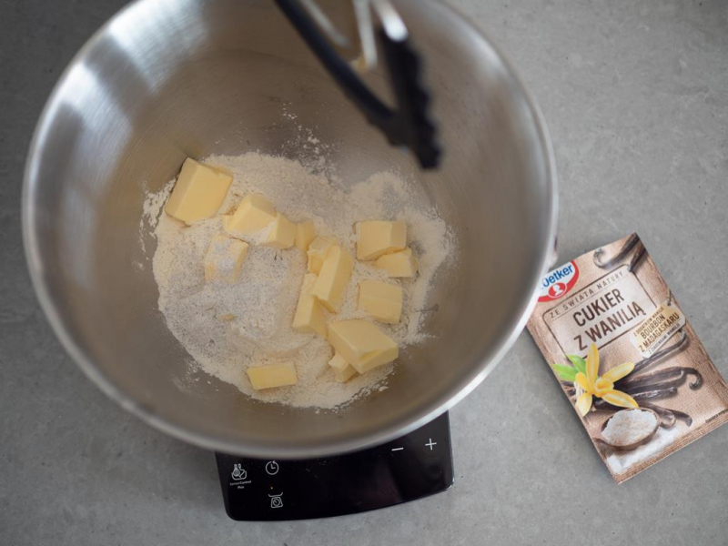 w misie mąka, cukier, pokrojone w kostkę masło, obok opakowanie cukru z wanilią