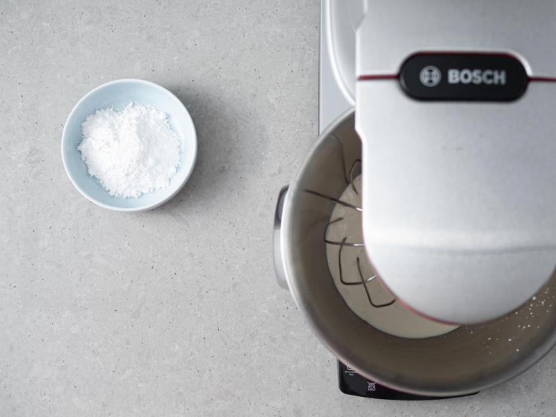 ubijanie śmietanki, obok miseczka z cukrem pudrem