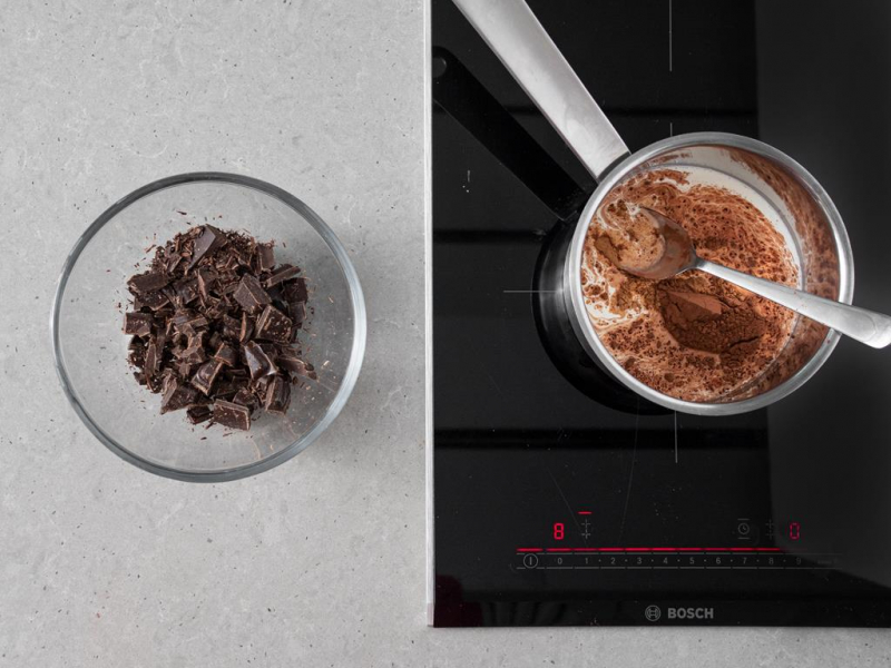 posiekana czekolada w miseczce, w garnuszku na palniku śmietanka z kakao