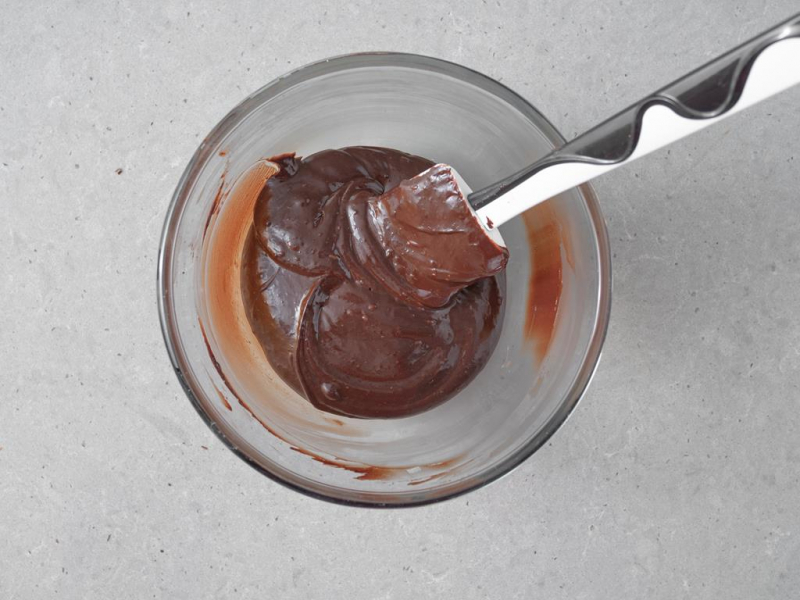 roztopiona czekolada w szklanej miseczce z silikonową łopatką