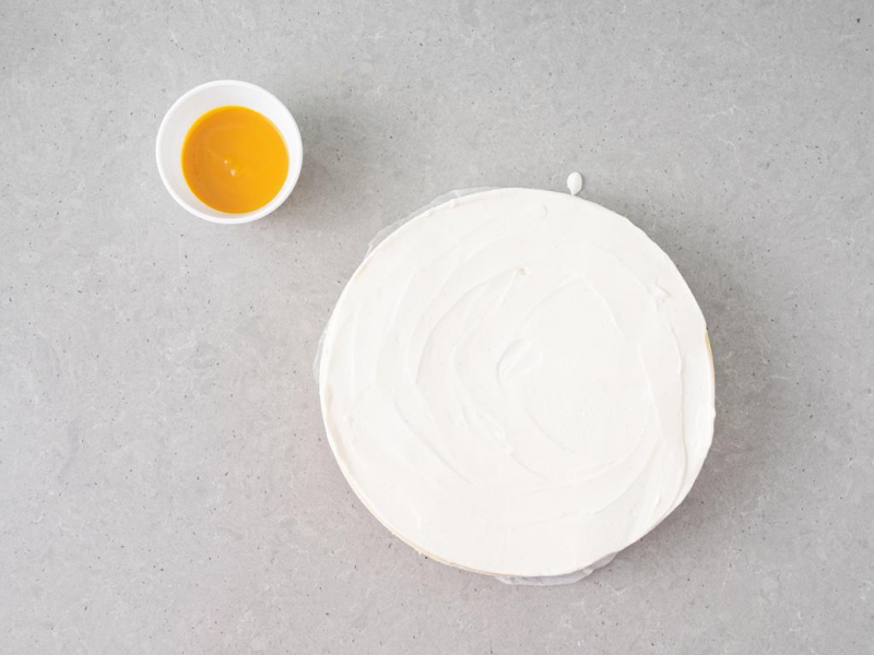 sernik oblany polewą z kwaśnej śmietany, miseczka z puree z marakui i mango