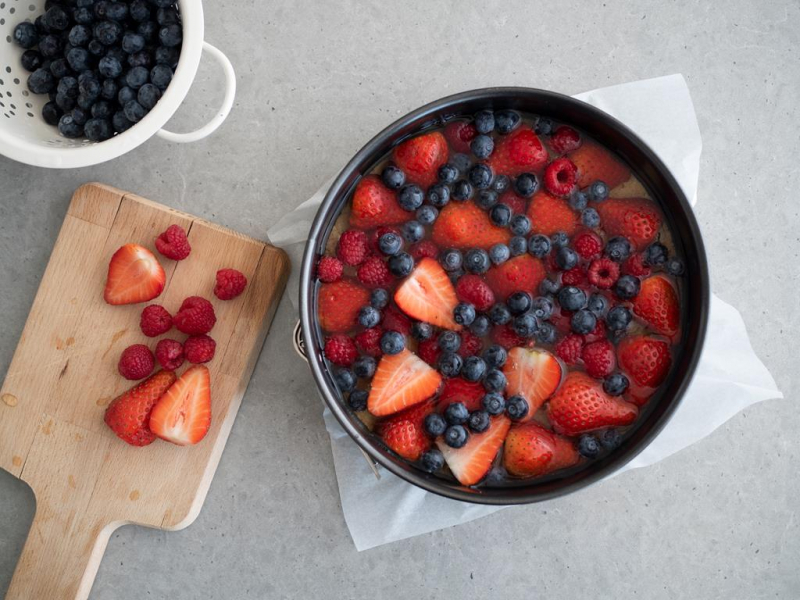 tortownica z galaretką, w niej zatopione truskawki, maliny i borówki