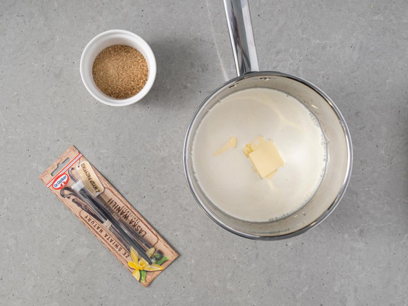 laska wanilii, miseczka z cukrem trzcinowym, garnuszek z mlekiem, 艣mietank膮 i mas艂em