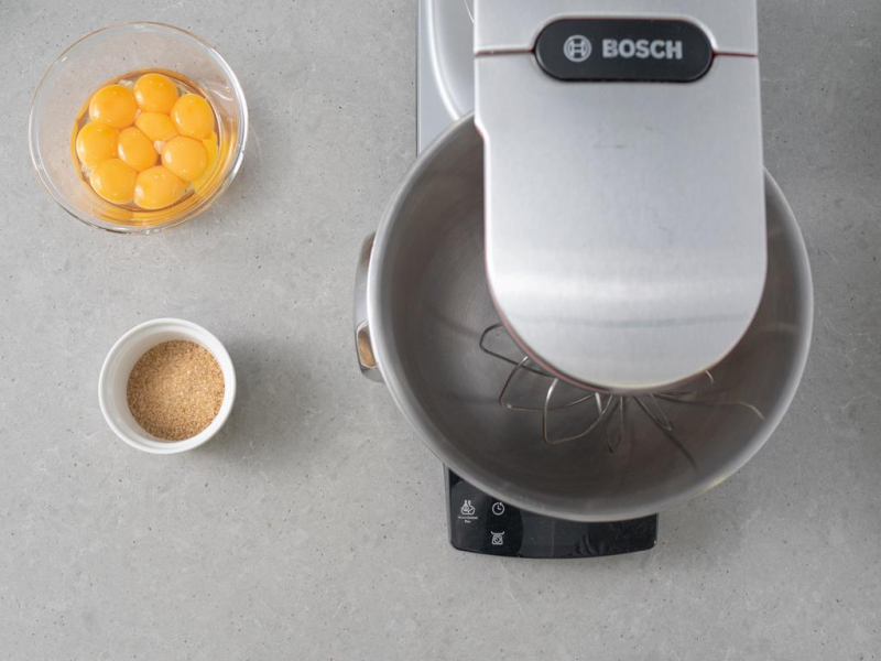 miseczka z 偶贸艂tkami, obok miseczka z cukrem trzcinowym i mikser planetarny