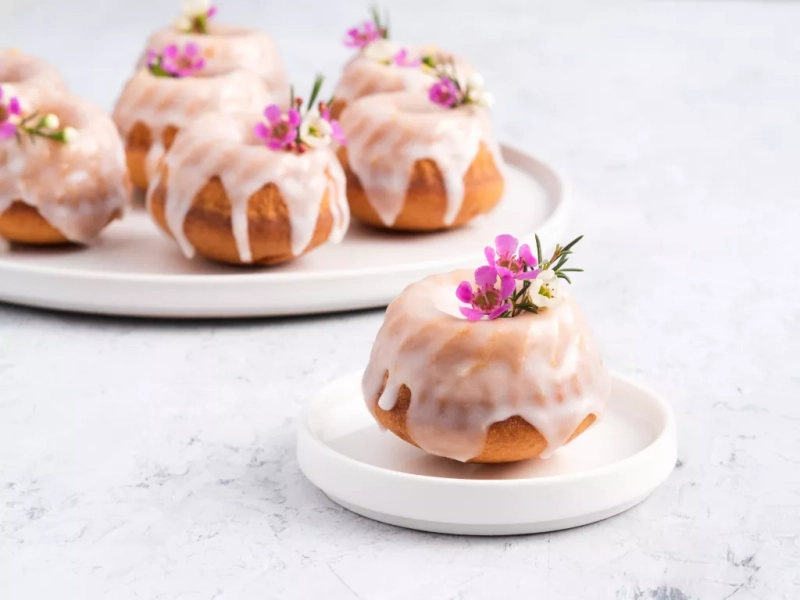 babeczki cytrynowe oblane lukrem i udekorowane fioletowymi kwiatkami