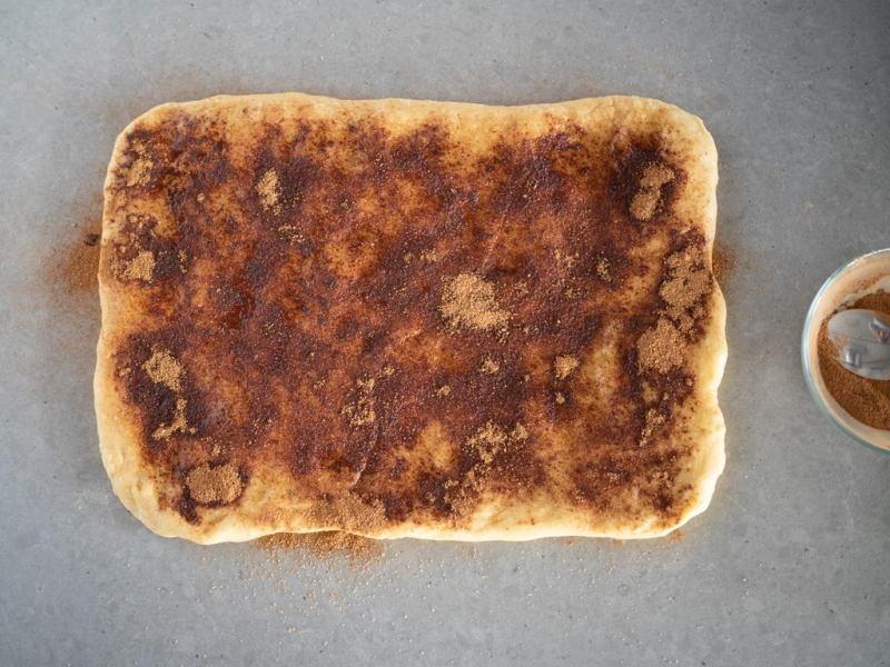 rozwałkowane ciasto drożdżowe posypane cukrem z cynamonem