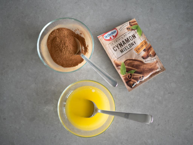 cynamon wymieszany z cukrem, obok miseczka z roztopionym masłem