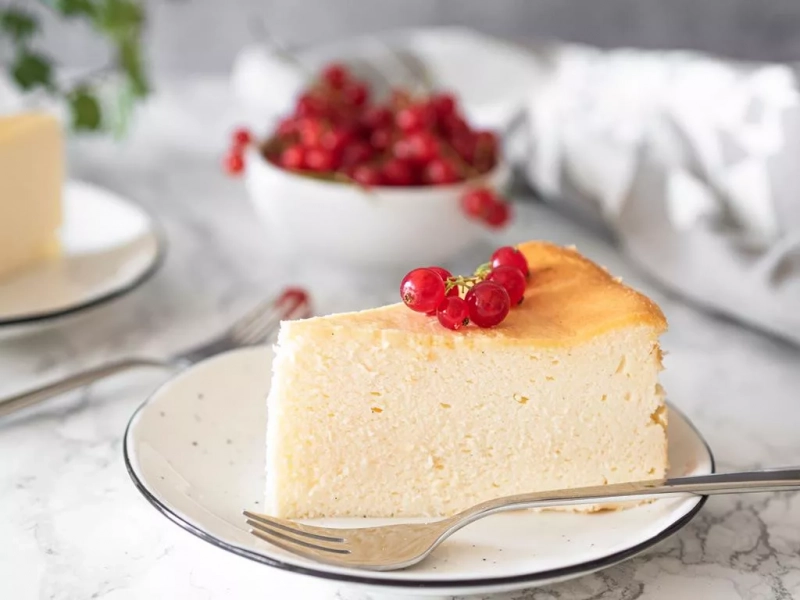 kawałek sernika bezglutenowego, udekorowany czerwoną porzeczką