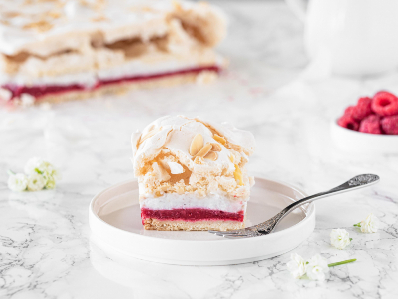 kawałek malinowej chrmurki wegańskiej na talerzyku z widelczykiem