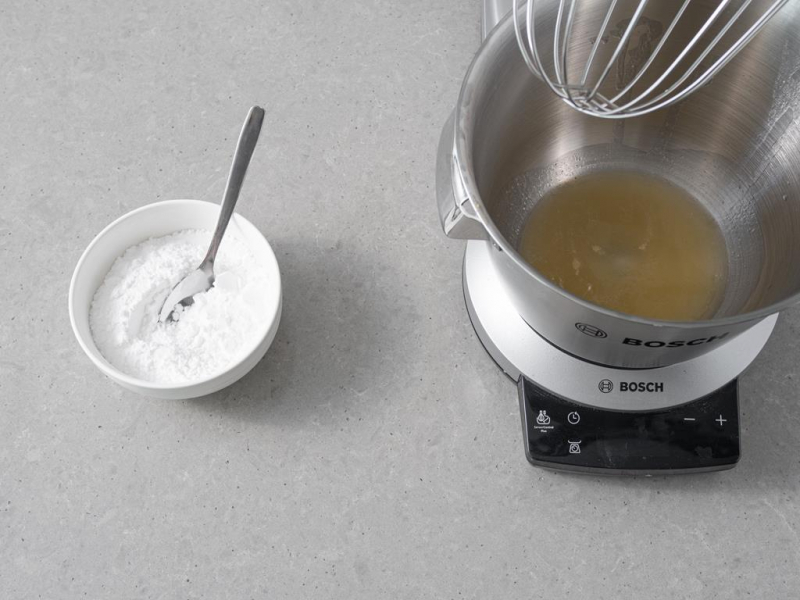 Aquafaba w misie. Obok w miseczce cukier wymieszany z cukrem pudrem.