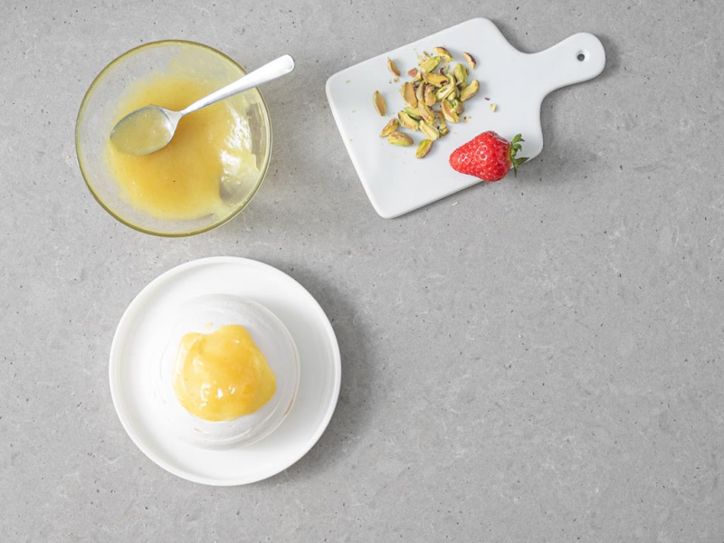 Na talerzyku mała wegańska beza. Obok lemon curd, pistacje i truskawki.