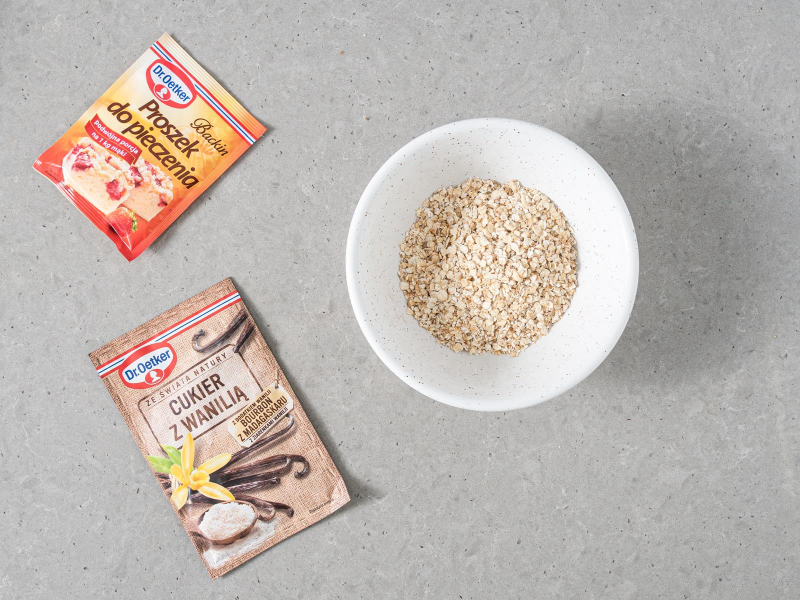 Płatki owsiane w miseczce. Obok cukier z wanilią i proszek do pieczenia Dr. Oetkera.
