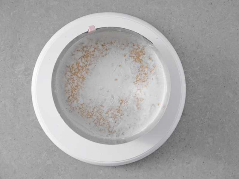 Tort w rancie cukierniczym, z rozsmarowanym na wierzchu kremem.