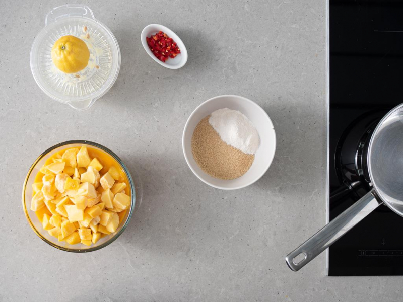 Pulpa z mango oraz kawałki mango w misce. Obok cukier kokosowy i żelfix w miseczce, oraz chili i sok z cytryny.