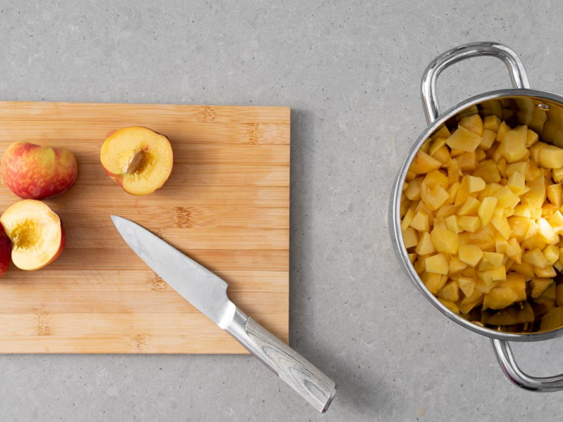 Krojenie brzoskwiń i pokrojone owoce w garnku.