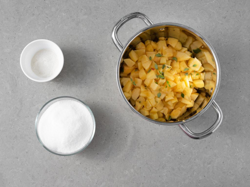 Pokrojone brzoskwinie w garnku razem z sokiem z cytryny i tymiankiem. Obok w miseczkach cukier oraz żelfix.