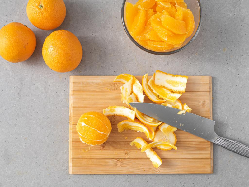 Filetowanie pomarańczy na drewnianej desce.