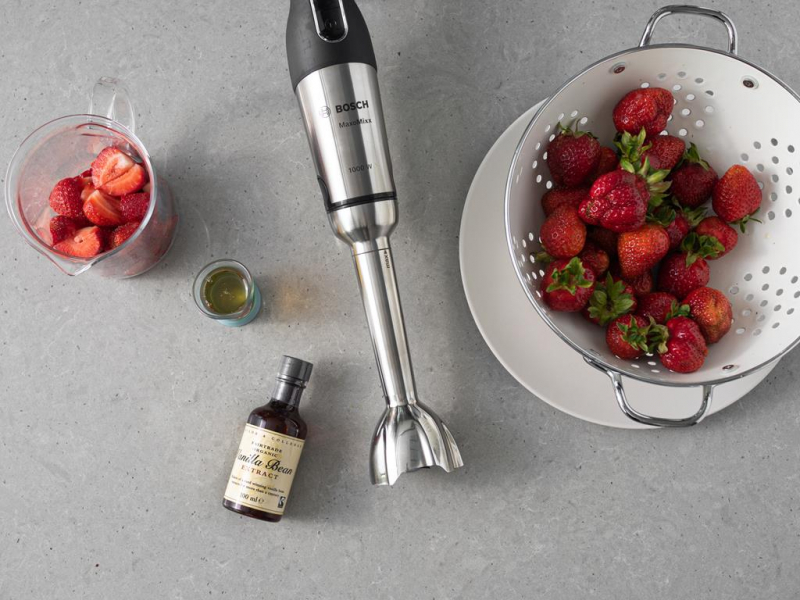 Truskawki w durszlaku. Obok blender firmy Bosch, ekstrakt z wanilii Taylor&Colledge i aquafaba,