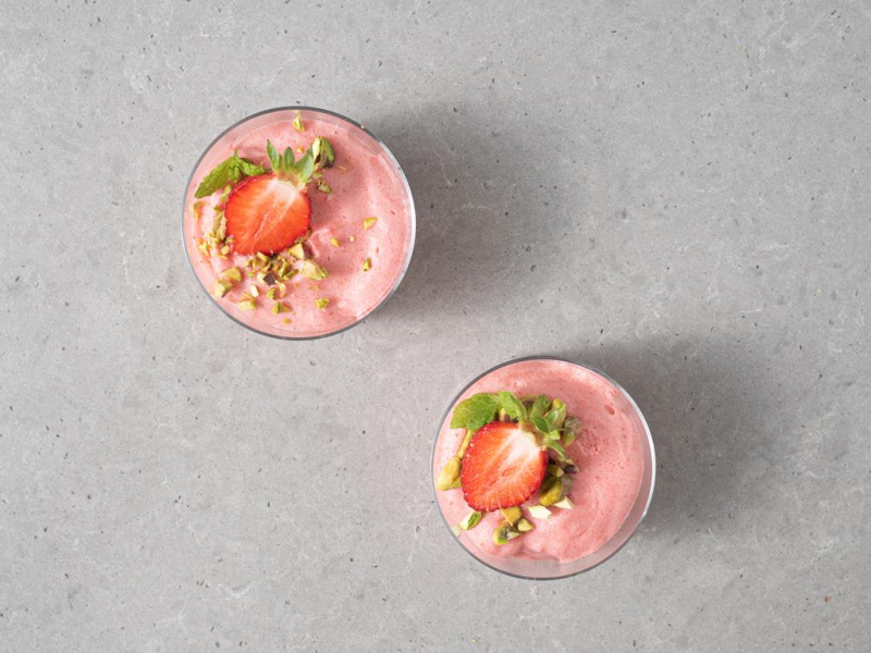 Wegański mus truskawkowy udekorowany pistacjami i truskawkami.