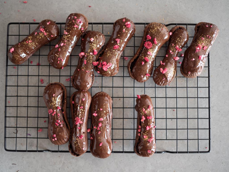 na kratce eklery z polewą czekoladową posypane złotą posypka i liofilizowanymi owocami