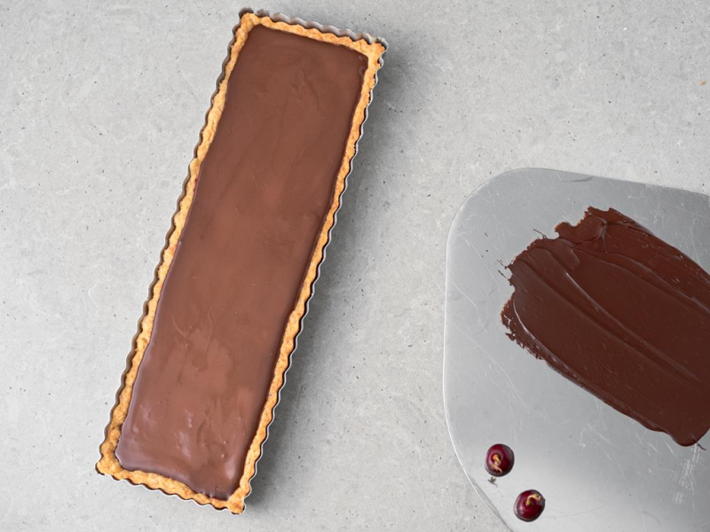 Wegańska czekoladowa tarta. Obok rozpuszczona czekolada.