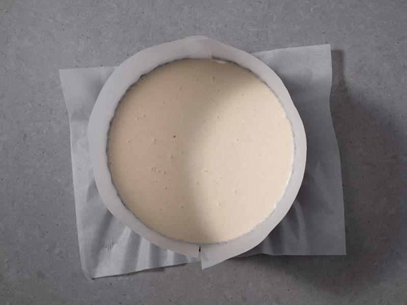 tortownica wyłożona papierem do pieczenia z wylaną masą na sernik baskijski