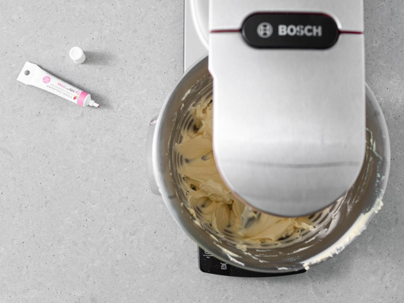 W misie utarta z cukrem pudrem margaryna wegańska. Obok barwnik różowy.