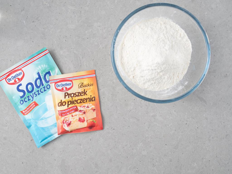 Soda oraz proszek do pieczenia na blacie. Obok wymieszane suche składniki w misie.