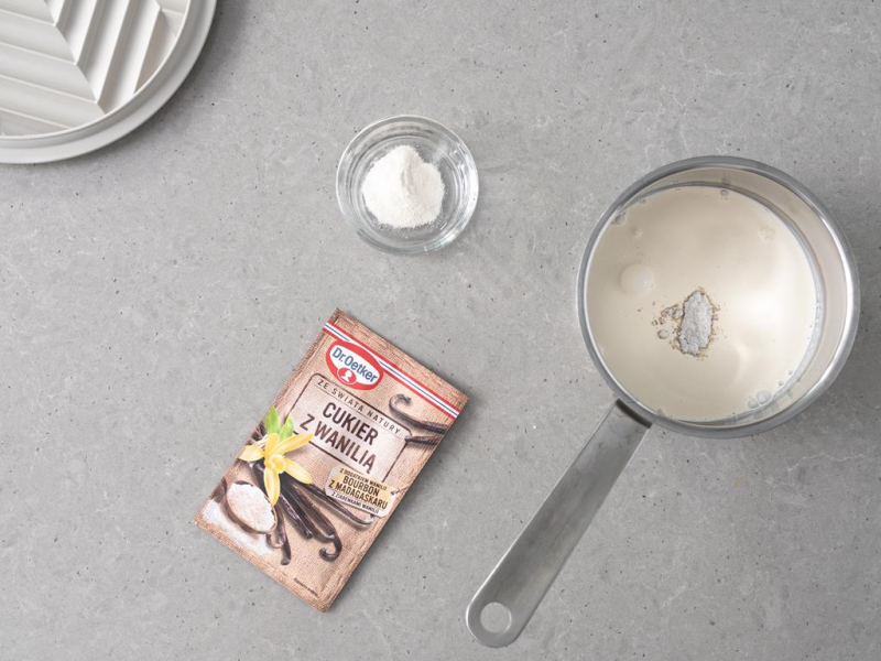 W garnku 艣mietanka wega艅ska z cukrem z wanili膮. Obok cukier z wanili膮 Dr. Oetkera.