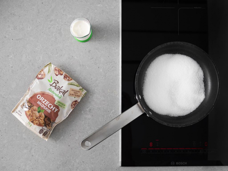 Orzechy Bakal na blacie. Obok cukier na patelni i wega艅ska 艣mietanka.