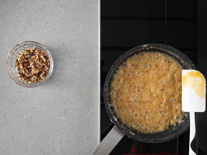 Karmel na patelni. Obok orzechy w艂oskie w miseczce.