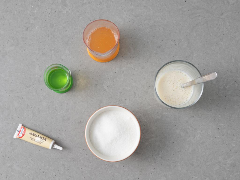 W szklance napój sojowy wymieszany z octem. Obok w misce cukier oraz olej, aquafaba i pasta z wanilii Dr. Oetkera.