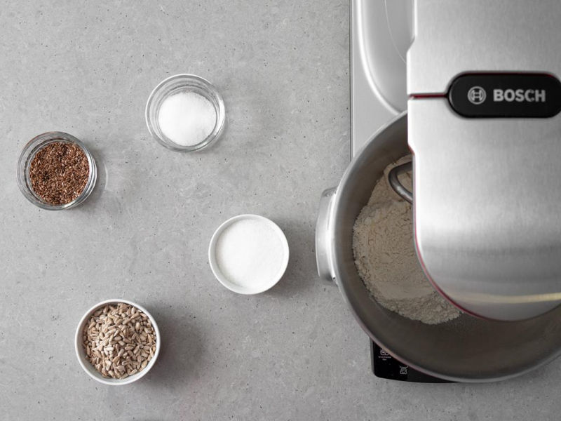 W misie wymieszane suche składniki. Obok cukier, sól, siemię lniane i pestki słonecznika w miseczkach.