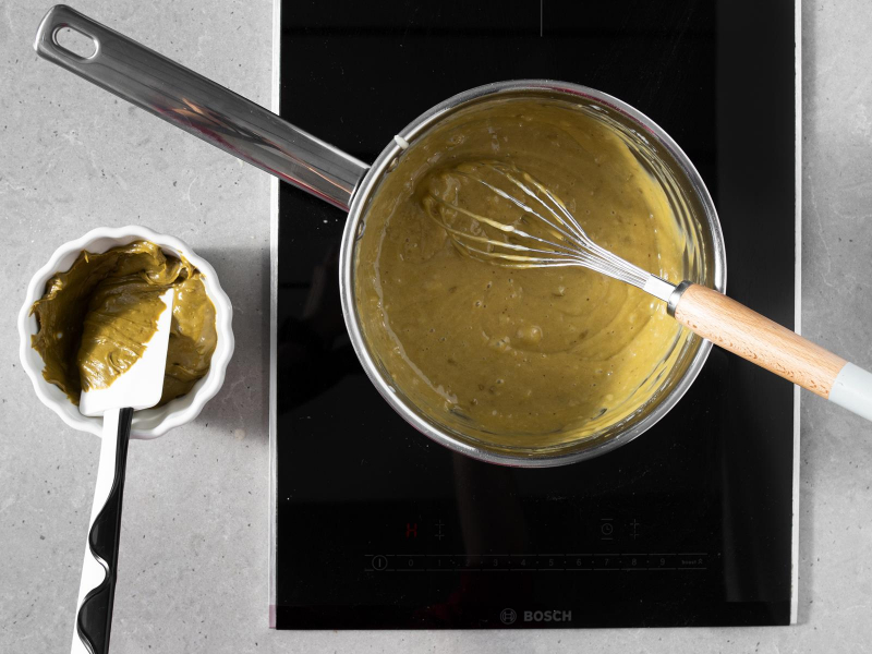 W garnku krem pistacjowy na tartę pistacjową, obok w miseczce pasta pistacjowa.