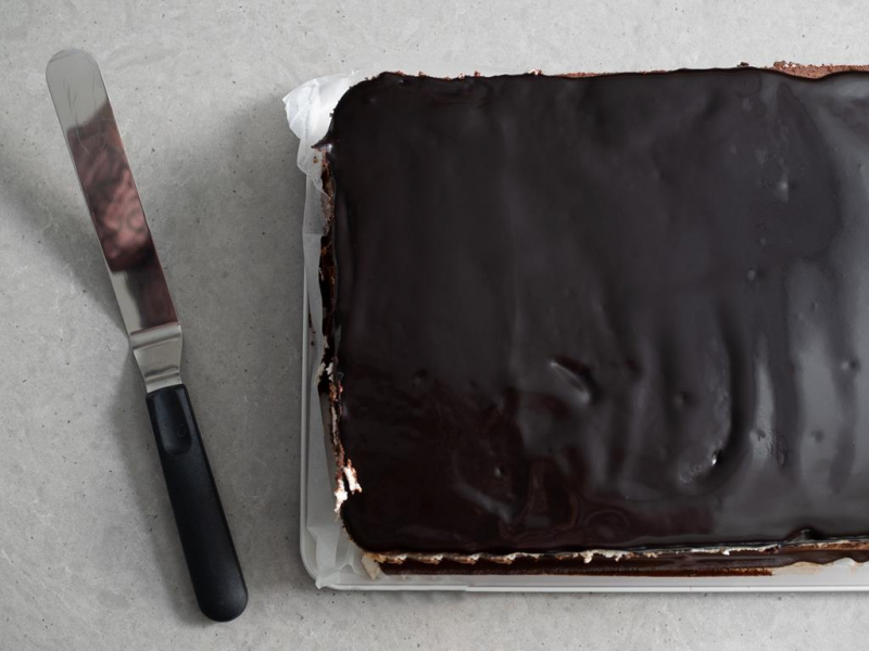 ciasto kukułka z polewą czekoladową obok duża szpatuła wilton