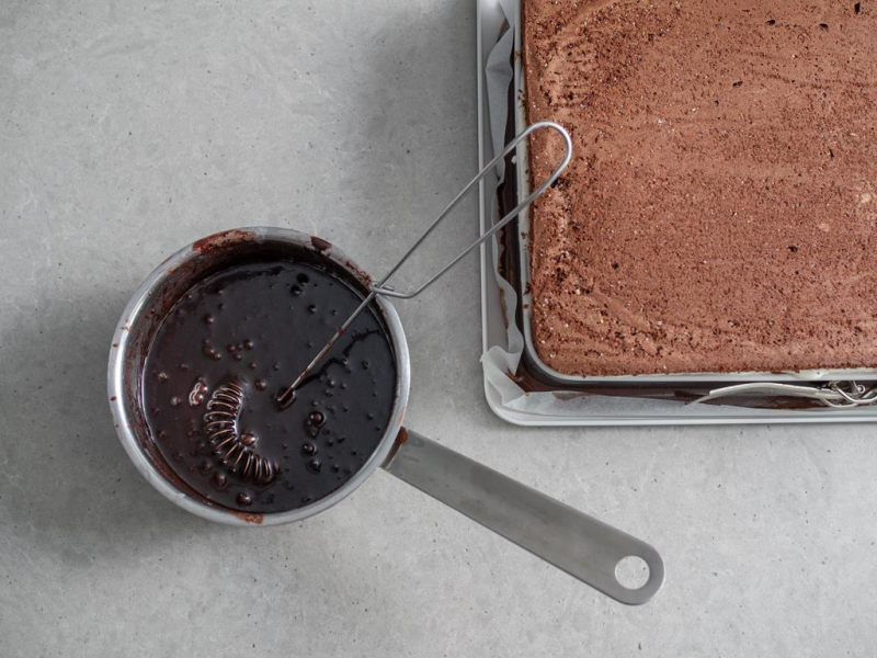 w rondelku polewa czekoladowa obok ciasto biszkoptowe w formie