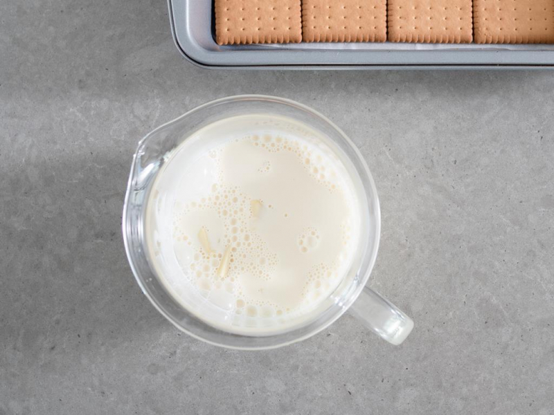 w szklanym naczyniu zalana biała czekolada gorącą śmietanką