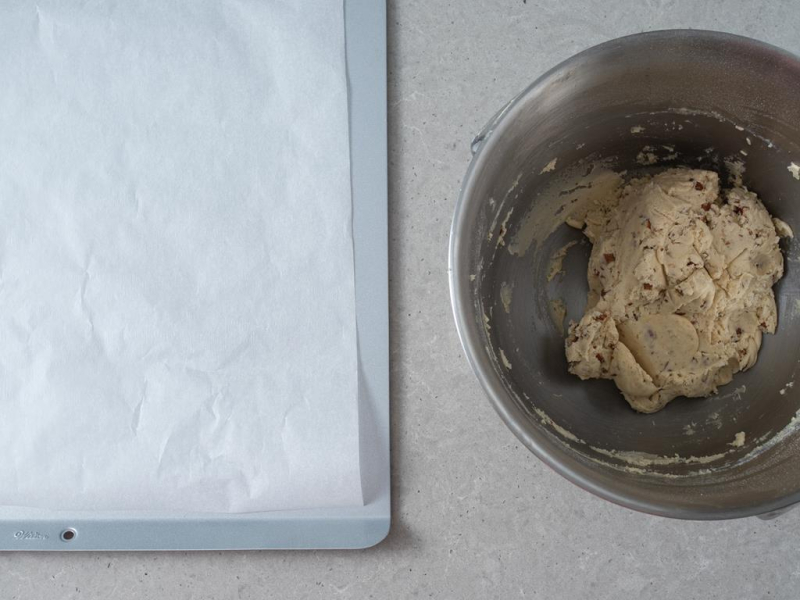 W misie zagniecione ciasto na śnieżne kule. Obok blacha na ciasteczka wyłożona papierem do pieczenia.