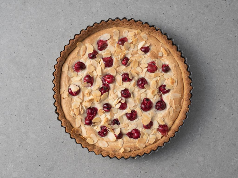 Upieczone roślinna tarta marcepanowa z żurawiną i płatkami migdałów.