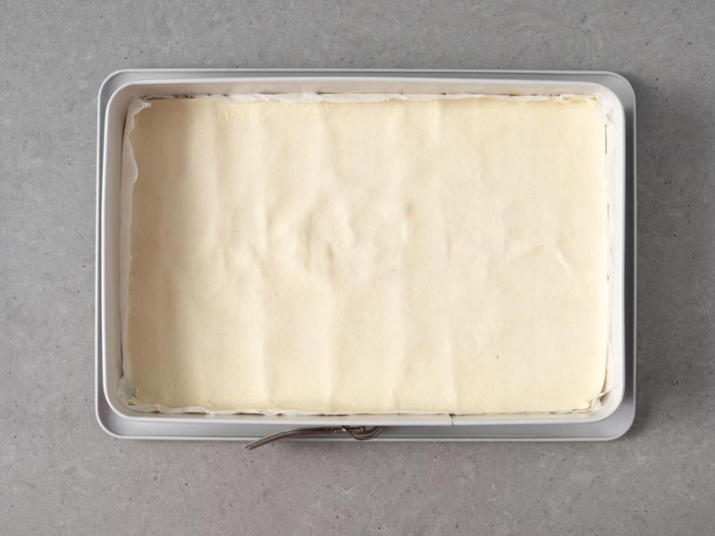 Blat ciasta francuskiego wyłożony w formie prostokątnej do pieczenia.