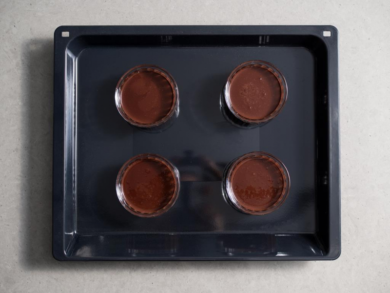 masa czekoladowa na  crème brûlée przelana do kokilek ustawionych na głębokiej blasze z wyposażenia piekarnika