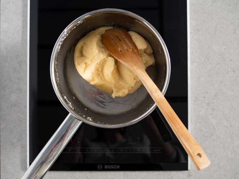 ciasto parzone w rondlu na palniku kuchenki i drewniana łyżka